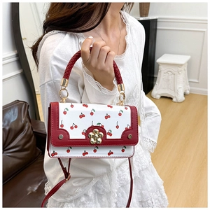 Chic white leather handbag with cherry print and golden flower lock held by a model