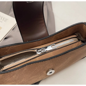 Macro detail of brown leather handbag with silver zipper and magnetic buckle closure