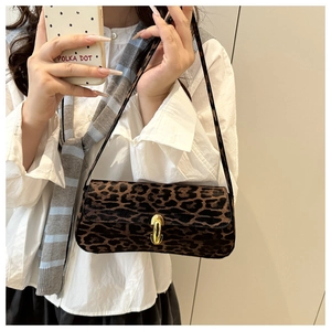 Close-up of leopard print baguette bag with gold metal clasp on model's shoulder