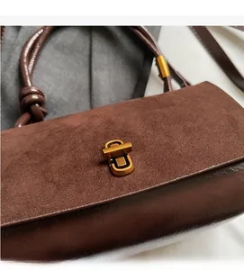 Close-up of chocolate brown suede handbag featuring vintage gold metallic twist lock detail