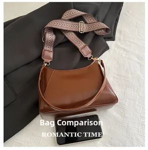 Size comparison of brown glossy shoulder bag with textured strap and mobile phone