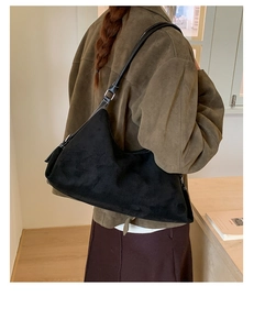 Detail of minimalist black suede hobo bag with sleek leather strap on model