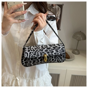 Macro detail of leopard print baguette bag with an oval gold metal buckle and fine texture