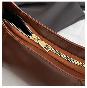 Detailed macro shot of smooth gold zipper hardware on vintage brown leather bag