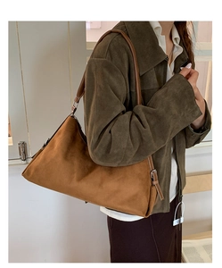 Detailed close-up of a caramel brown suede shoulder bag with adjustable silver buckle strap