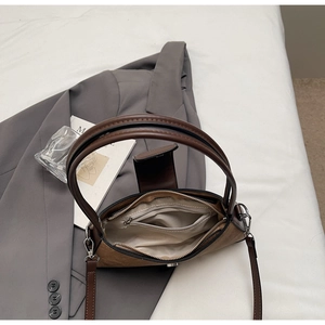 Detailed interior of a brown faux leather baguette bag with zip pocket and textile lining