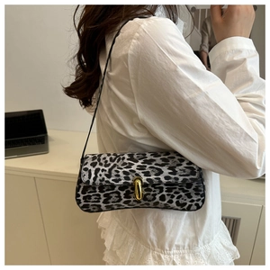 Detail of grey leopard print baguette bag with golden U-shaped clasp worn by a model