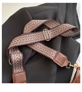 Macro shot of multi-color woven shoulder strap with leather ends and golden hardware