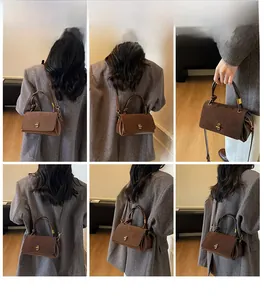 Detail of brown suede crossbody bag with vintage metal lock and leather handle