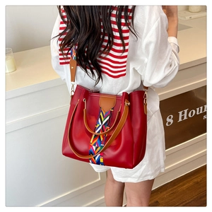 Detail of red PU leather tote bag with colorful geometric woven strap and leather handles