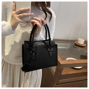 Détail du sac à main noir avec logo doré Fashion & Bags et pendentifs élégants