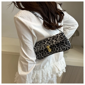 Close-up of leopard print baguette bag with gold metal clasp on a white lace shirt