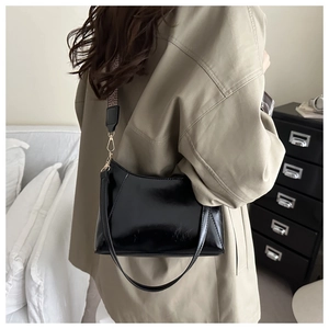 Glossy black baguette bag with dual shoulder straps shown on a model side view