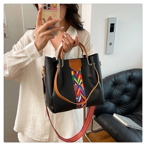 Detail of black tote bag featuring ethnic woven stripes and brown circular top handles