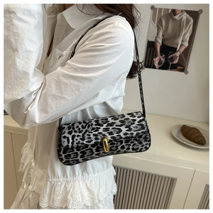 Detail of leopard print baguette bag with golden metal buckle and textured slim shoulder strap