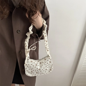White corduroy pleated shoulder bag with brown bows and heart patterns on female model