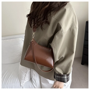 Detail view of a vintage brown leather baguette bag with premium gold metal hooks
