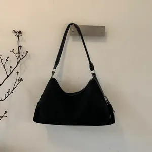 Close-up of black suede moon bag with silver metal buckle hanging on a wall