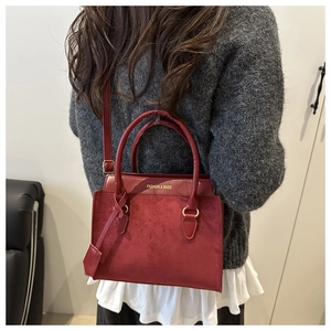 Mannequin avec un sac à main bordeaux, double poignée et détail de breloque latérale