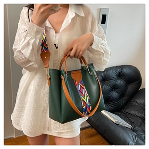 Detail of dark green leather handbag with stylish colorful geometric woven shoulder strap