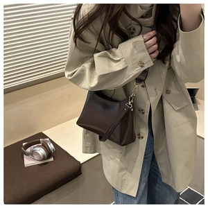 Detail of dark brown leather baguette bag with golden buckle and sleek urban silhouette