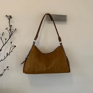 Detail view of brown suede hobo bag with contrast stitching and silver metal hardware