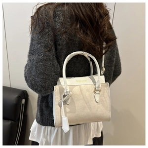 Détail du sac à bandoulière crème avec l'inscription dorée Fashion & Bags sur le devant
