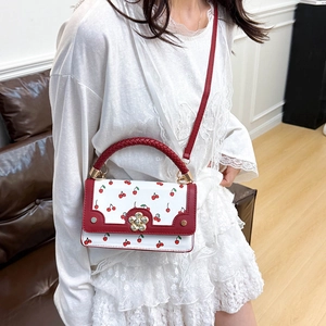 Women's white cherry print leather crossbody bag with red woven handle and flower clasp