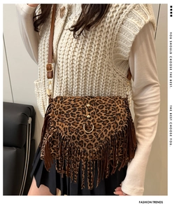 Detail shot of leopard print fringe bag with golden hardware and long suede tassels