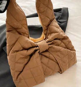 Macro detail of caramel brown quilted tote bag with a large decorative bow