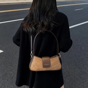 Brown vintage suede baguette bag with metal buckle shown on model in minimalist style