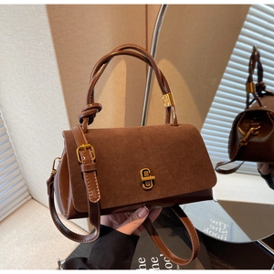 Detail of suede crossbody bag showing golden twist lock and knot handle texture