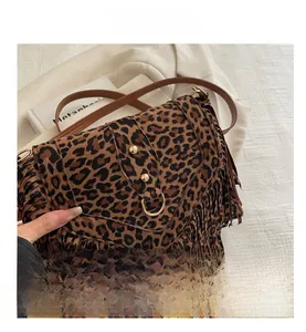 Macro detail of leopard print suede crossbody bag featuring long fringes and gold ring buckle
