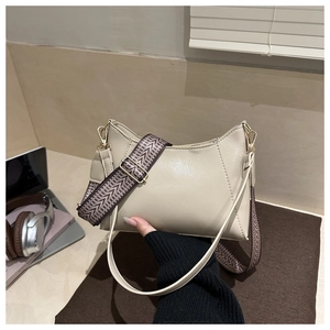 Detail of minimalist cream underarm bag showing interchangeable woven and leather straps