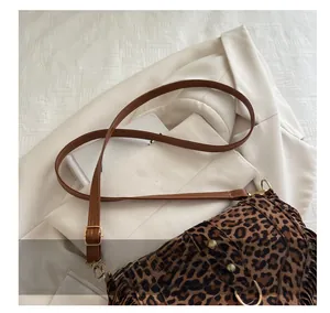 Close-up of leopard print saddle bag with brown leather strap on a chic blazer