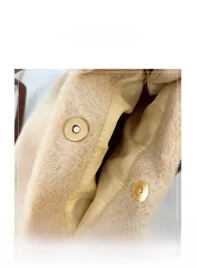 Gros plan détaillé des boucles magnétiques dorées sur le sac cabas en peluche beige