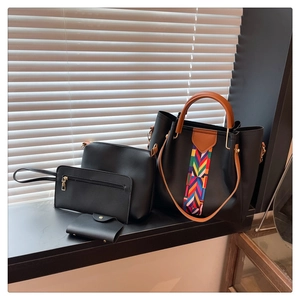 Detail of 4-piece black tote bag set featuring rainbow woven straps on a black windowsill