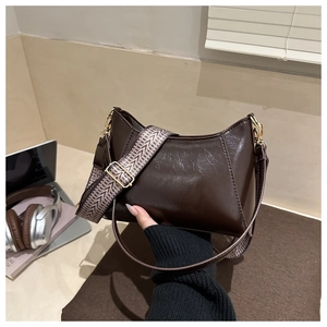 Detail of dark brown leather underarm bag with chic woven strap and smooth texture