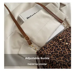Detail of adjustable golden buckle and brown fringe on leopard print saddle bag