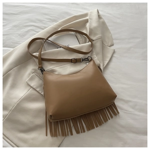Dettaglio borsa a tracolla in ecopelle marrone con lunghe nappe su sfondo bianco