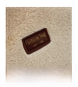 Gros plan détaillé sur l'écusson logo en cuir marron d'un sac cabas en peluche
