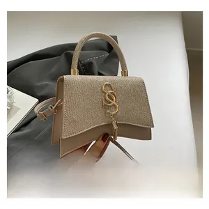 Detailed view of beige sequin shoulder bag with gold metal logo and tassel accents
