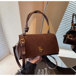 Macro shot of dark brown suede stitching and golden metal twist lock on tote bag