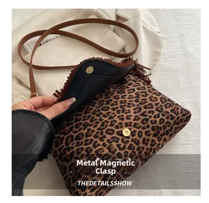 Detail of the magnetic buckle closure and leopard print texture on a tassel shoulder bag