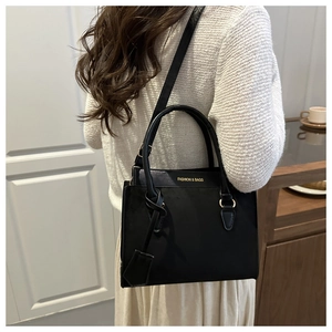Détail d'un sac à bandoulière en similicuir noir élégant avec texte doré et anneaux