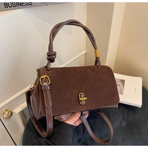 Close-up of caramel suede crossbody bag with gold lock and knotted handle detail