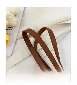 Gros plan de la poignée en cuir marron avec des détails précis de double couture
