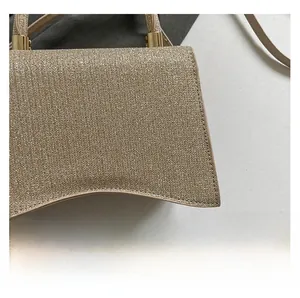 Detail of champagne gold glitter fabric and curved handle on luxury mini flap bag