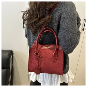Détail du sac bandoulière bordeaux en patchwork avec dorures porté par un mannequin