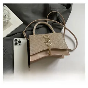 Detail view of stylish beige handbag with sequined flap and decorative S-shaped metal logo